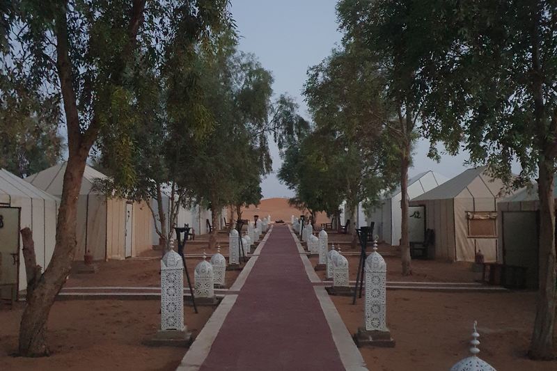Stanový kemp v Erg Chebbi za soumraku s lucernami podél cesty